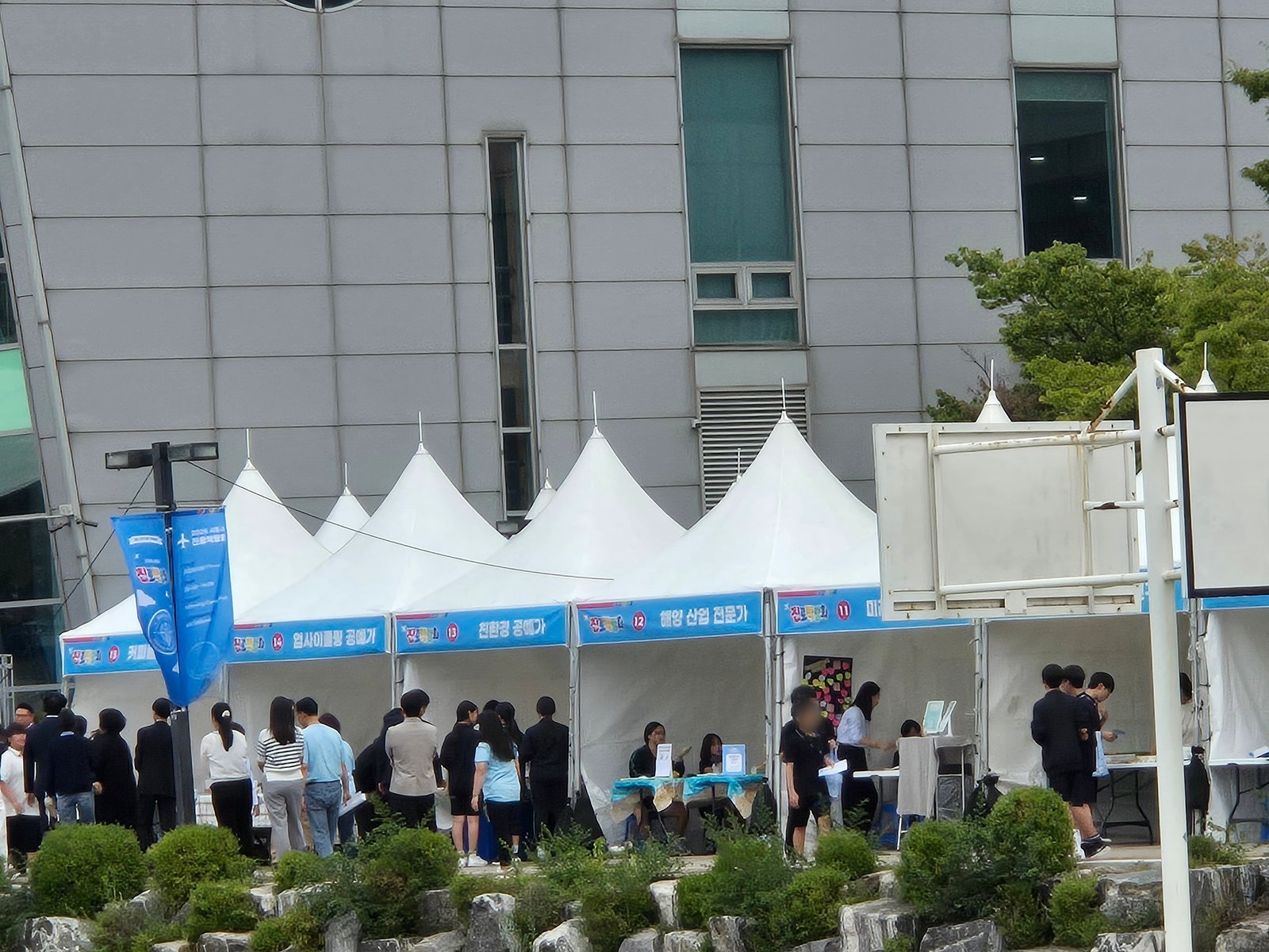 Career fair marquees in front of a GTEC building: the upcycling, eco-friendly craft, and marine industry booths, with teenagers gathered at each